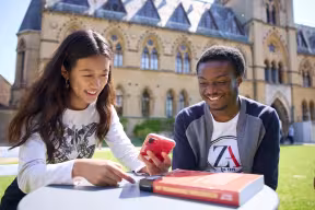 Students on a phone in front of the Museum of Natural History