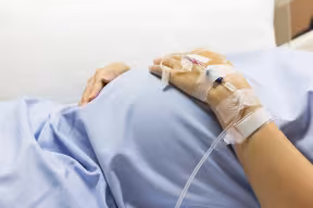 An Asian pregnant woman patient lying on a hospital bed on a drip receiving a saline solution on bed VIP room at hospital.