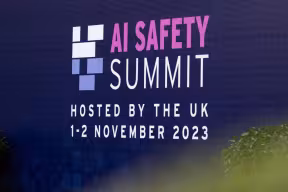 UK AI Safety Summit Day One in block writing against a background of blue merging into yellow.