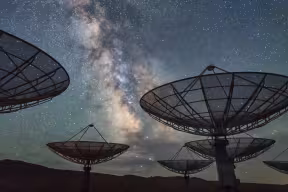 A radio telescope observatory under a starry night sky.