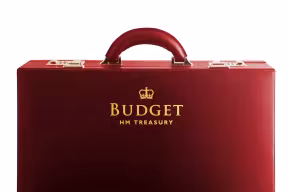 A red briefcase with the words ‘Budget HM Treasury’ on the side and an icon of a crown – the UK Government logo.