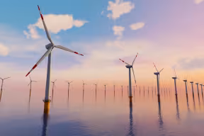 A line of offshore wind turbines standing in the sea.