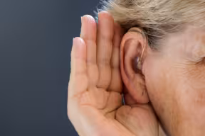 Photo | Elderly woman with hearing aid on grey background. Close up.