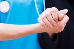 Nurse holding an elderly person's hand