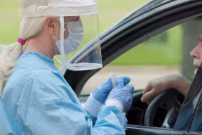 Nurse testing a man in car for coronavirus