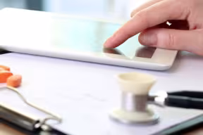 Doctor on tablet with pills and stethoscope 