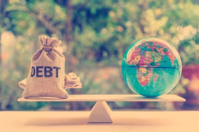 Money bag and toy globe balancing on scales