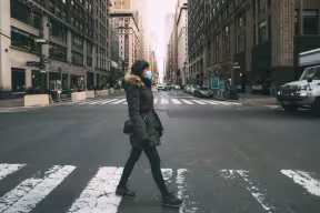 Woman crossing urban street wearing face mask