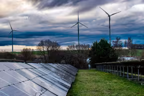 A photograph of solar panels and wind turbines