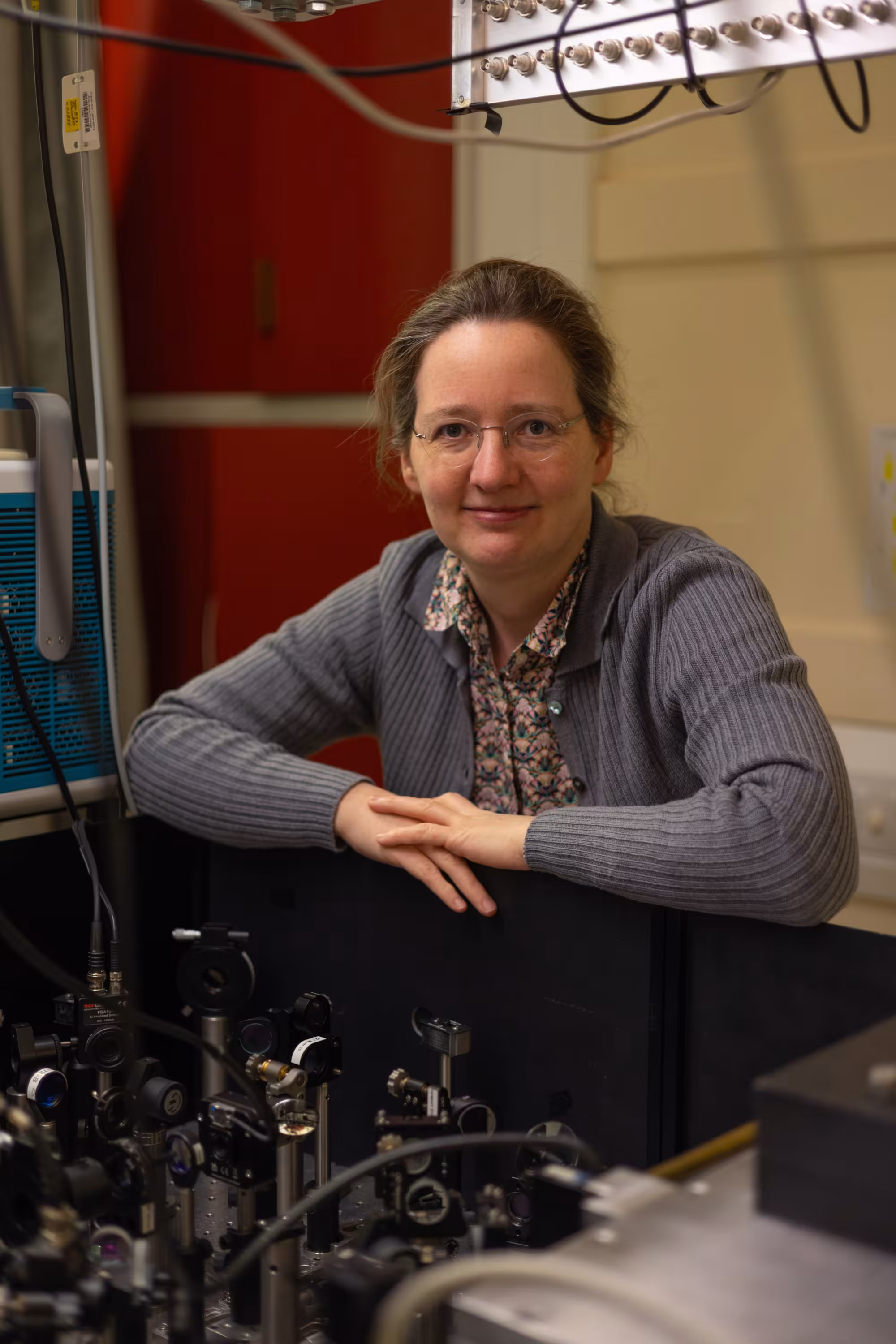 Professor Laura Herz leaning with equipment used to measure semiconductor performance.
